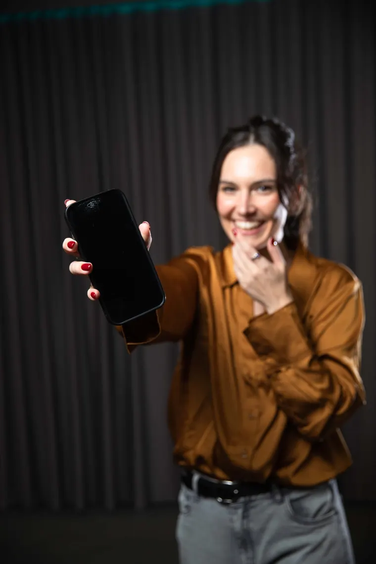 Tess in an ochre shirt holding her phone, about to start a conversation